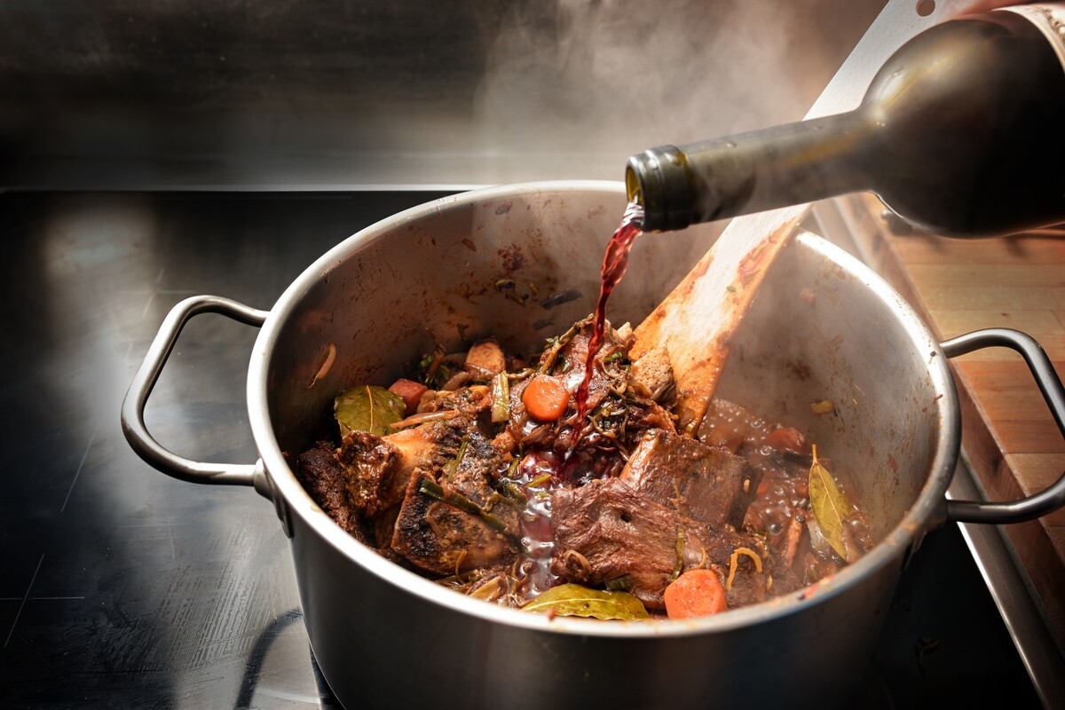 Aggiunta vino rosso in pentola di carne con soffritto