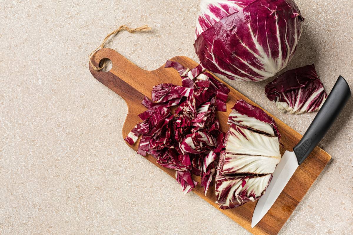 Vista dall'alto cespo di radicchio tagliato al coltello su tagliere di legno