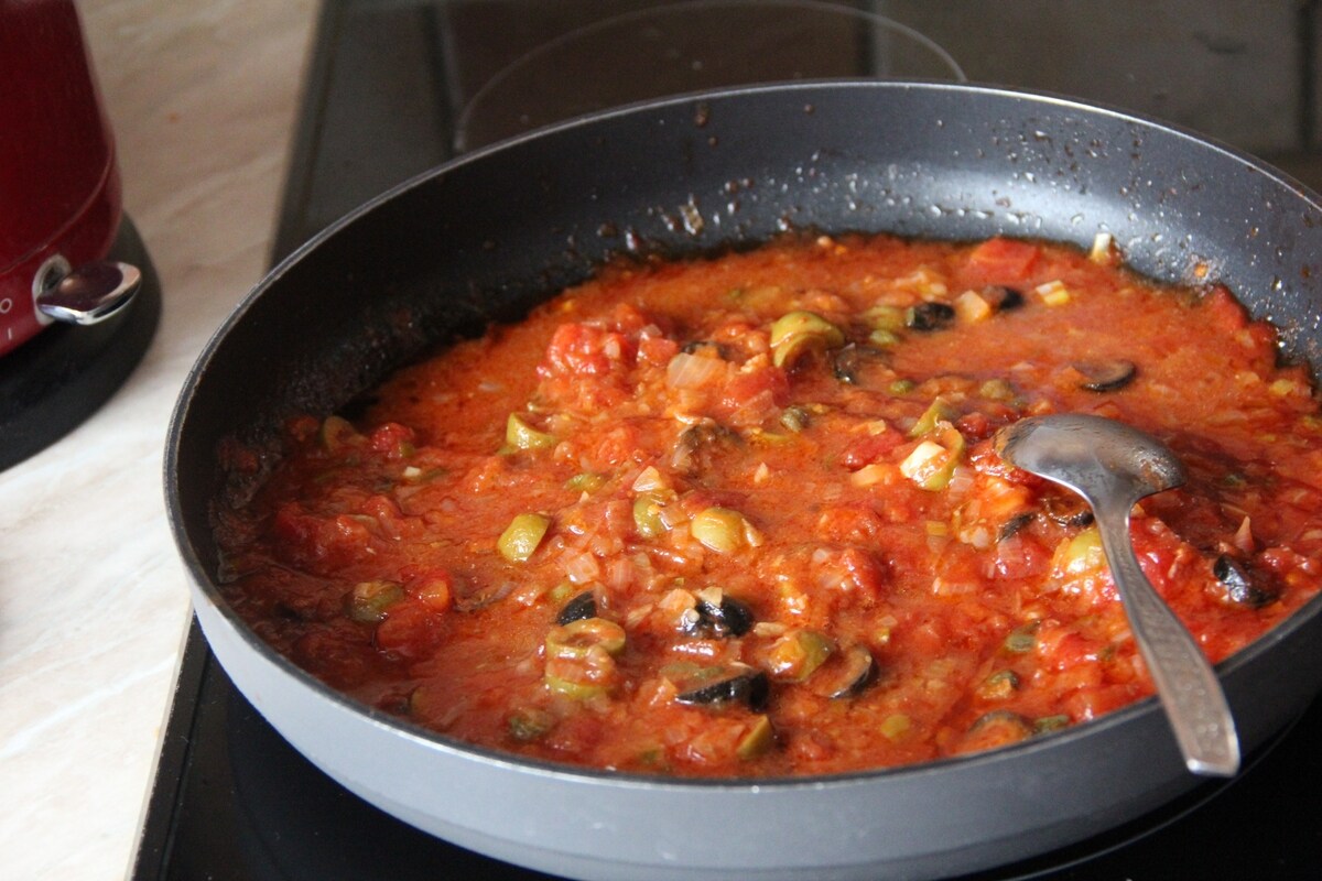 Padella con pomodoro, tonno, olive e capperi in cottura