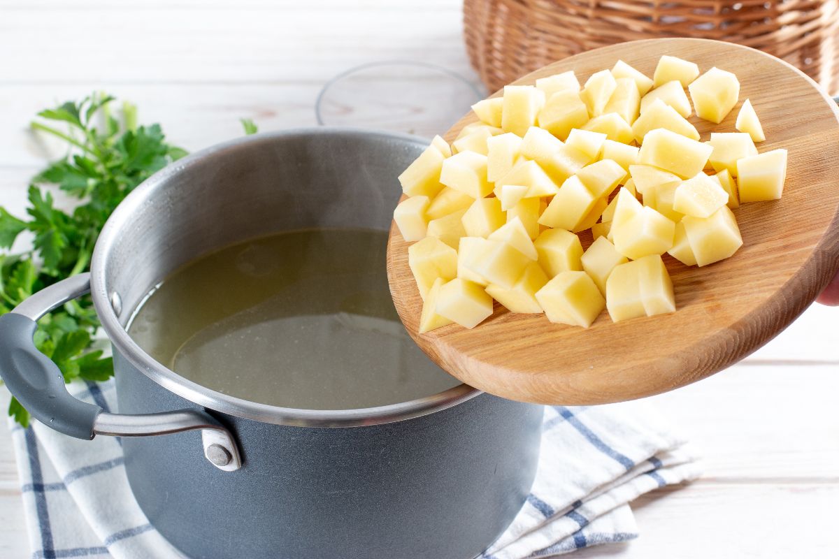Pentola di acqua in cui stanno per essere tuffate patate a dadini da cuocere 