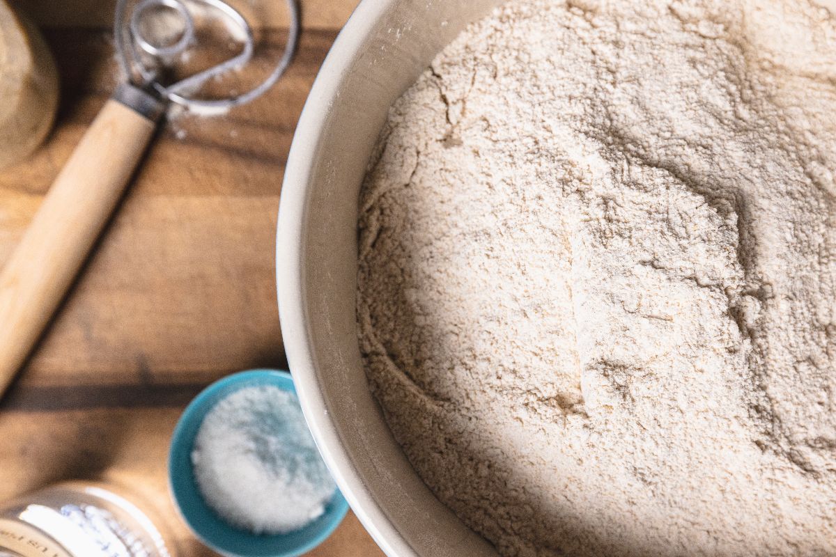 Ciotola con farina e vicino sale e attrezzo per impastare
