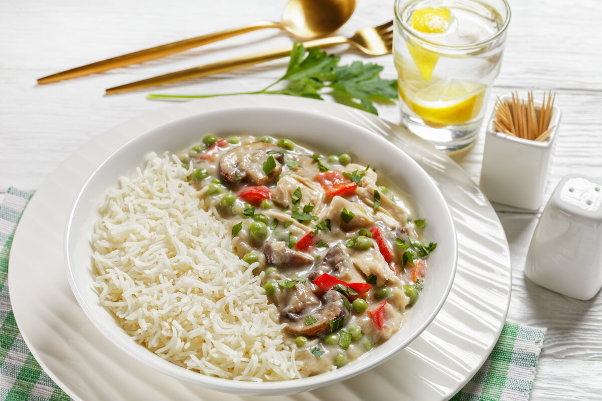 Piatto con riso e pollo alla king con peperoni, funghi e piselli