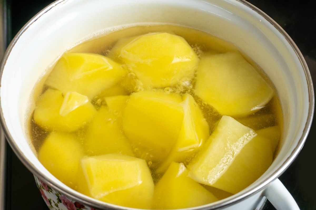 Pentola con patate a pezzi in cottura