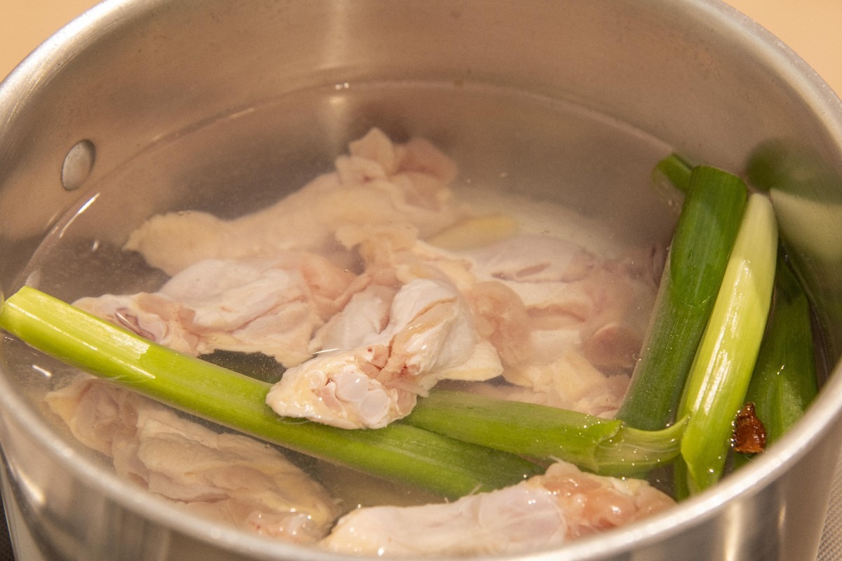 Brodo per ramen con carcasse di pollo e cipollotto in cottura
