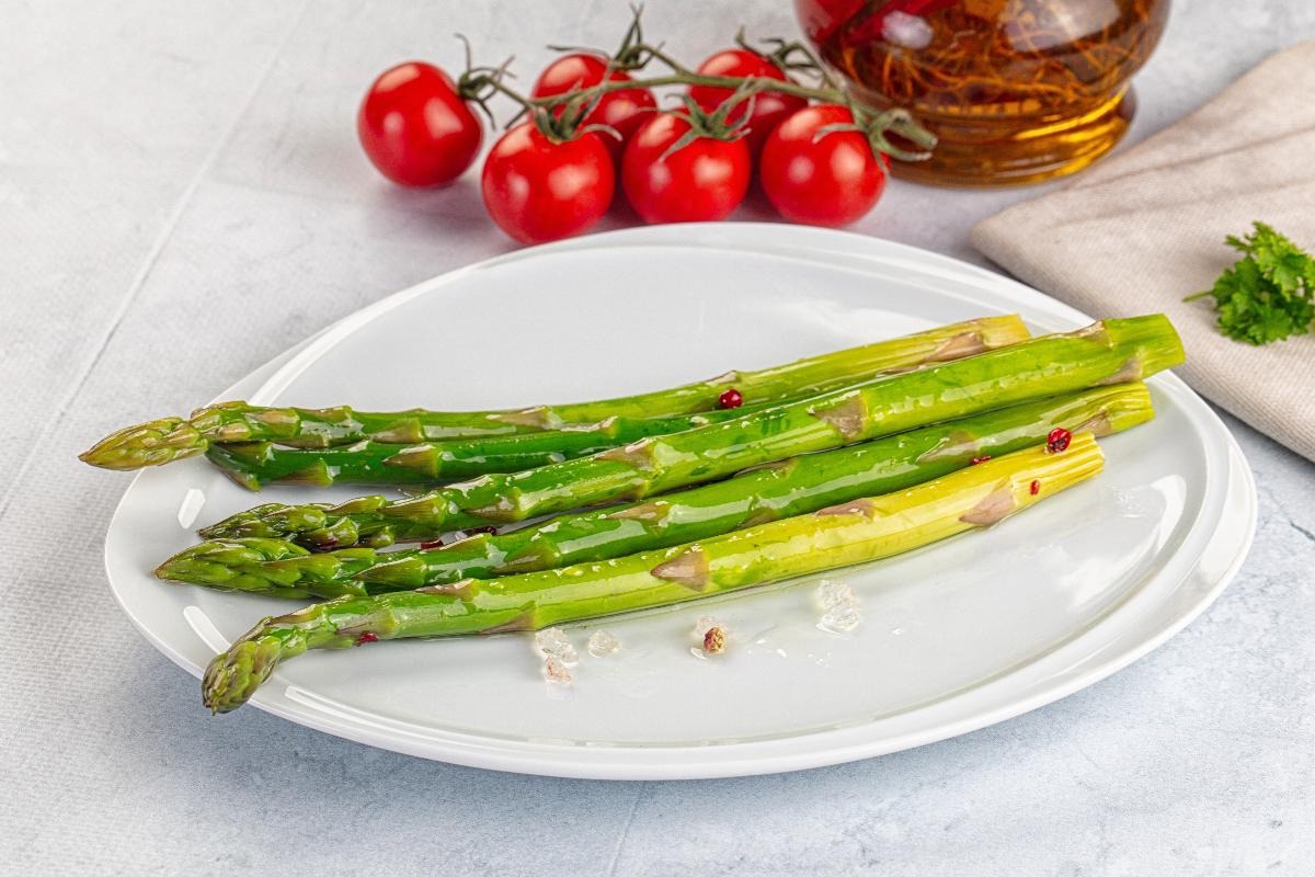 Piatto con asparagi lessati e pomodorini sullo sfondo