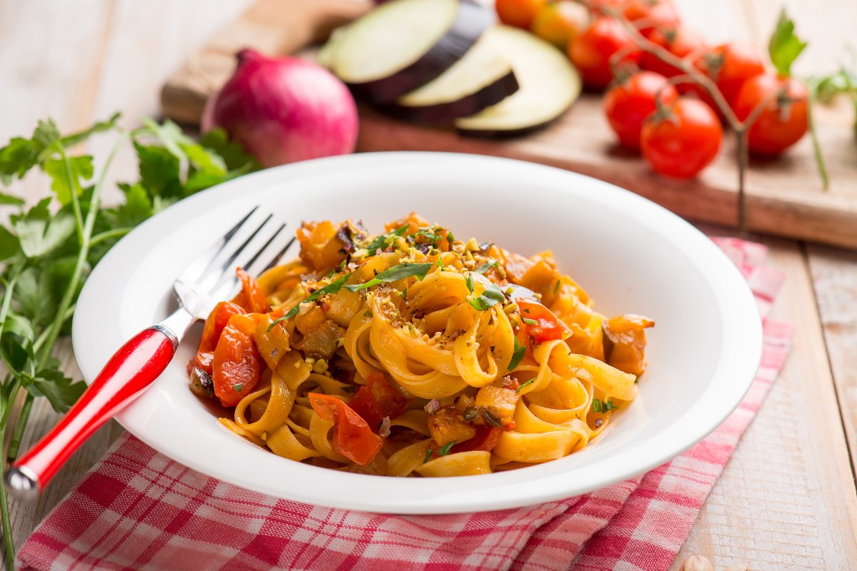 Piatto di pasta tipo tagliatelle condito con sugo di melanzane e pomodorini