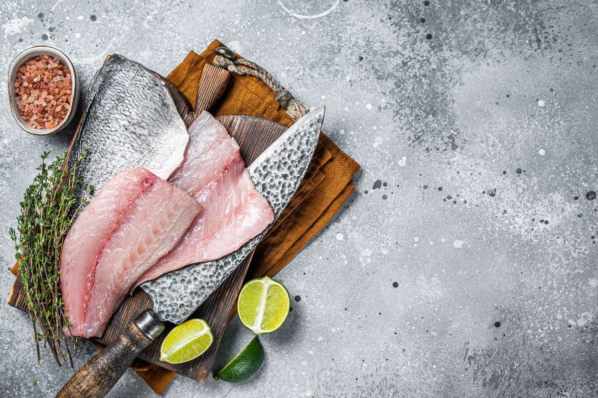 Filetti di orata su tagliere di legno con vicino coltello