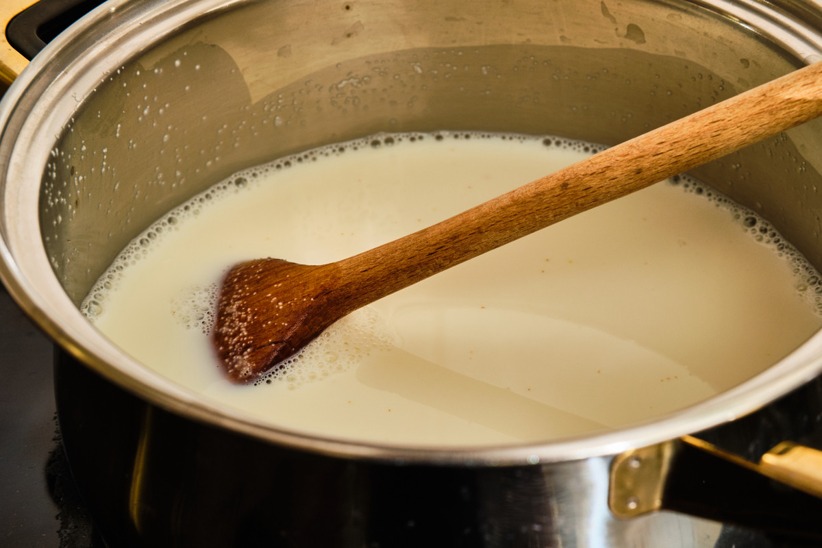 Pentola con latte e cucchiaio di legno con semolino in cottura