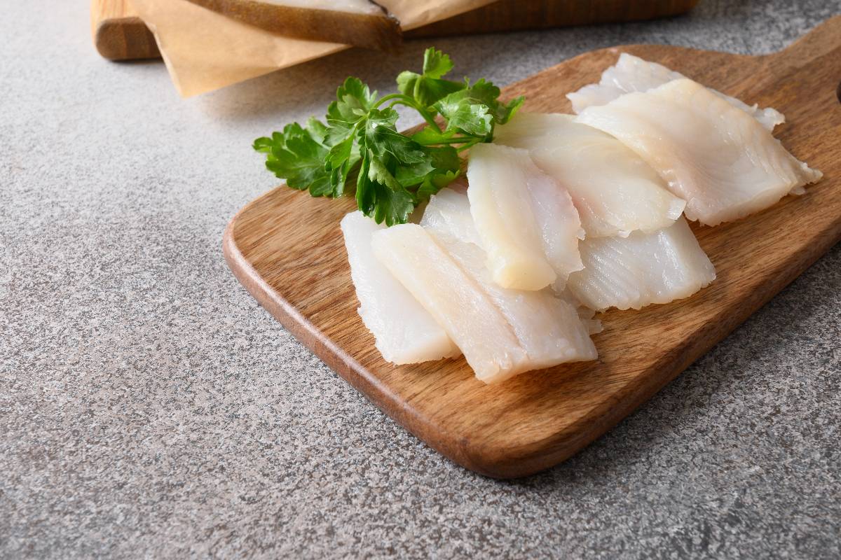 Tagliere di legno con filetti di pesce crudo e prezzemolo fresco a decorazione
