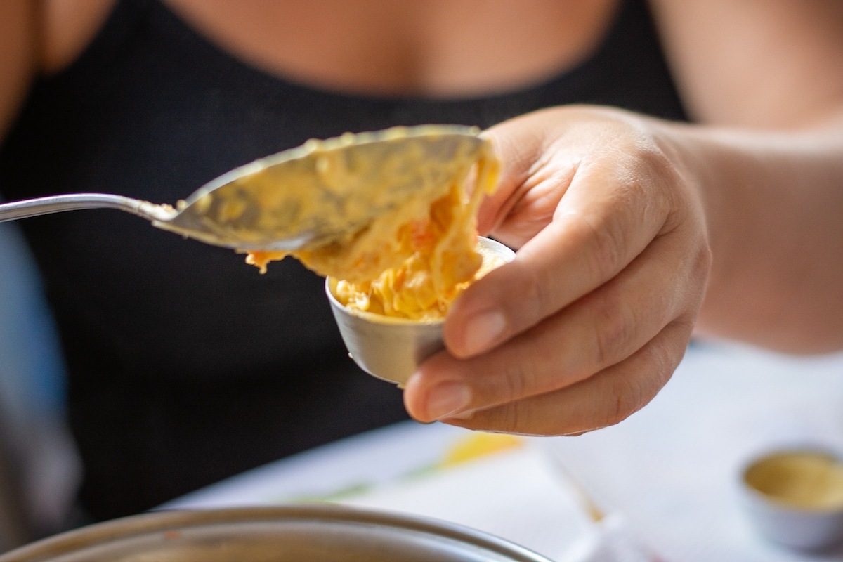 Donna che riempie con un cucchiaio il cestino di pasta frolla