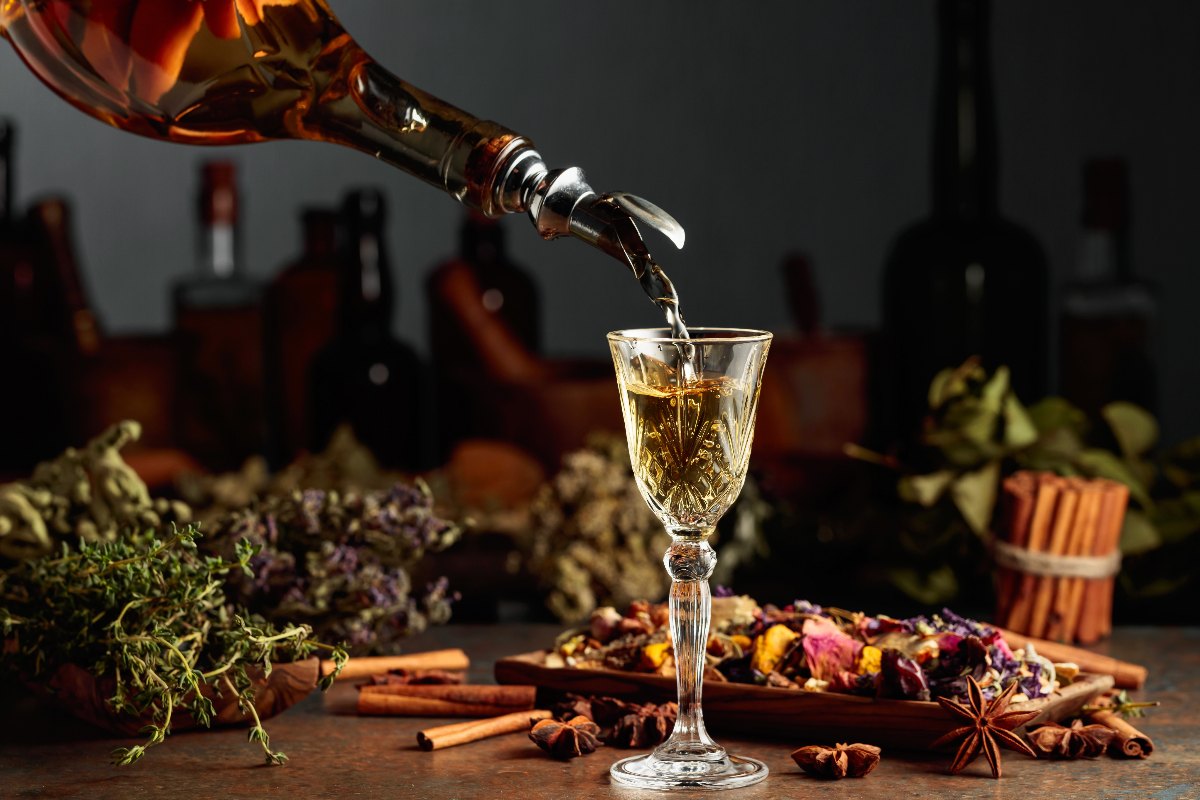 Liquore color paglierino versato da una bottiglia in un bicchierino