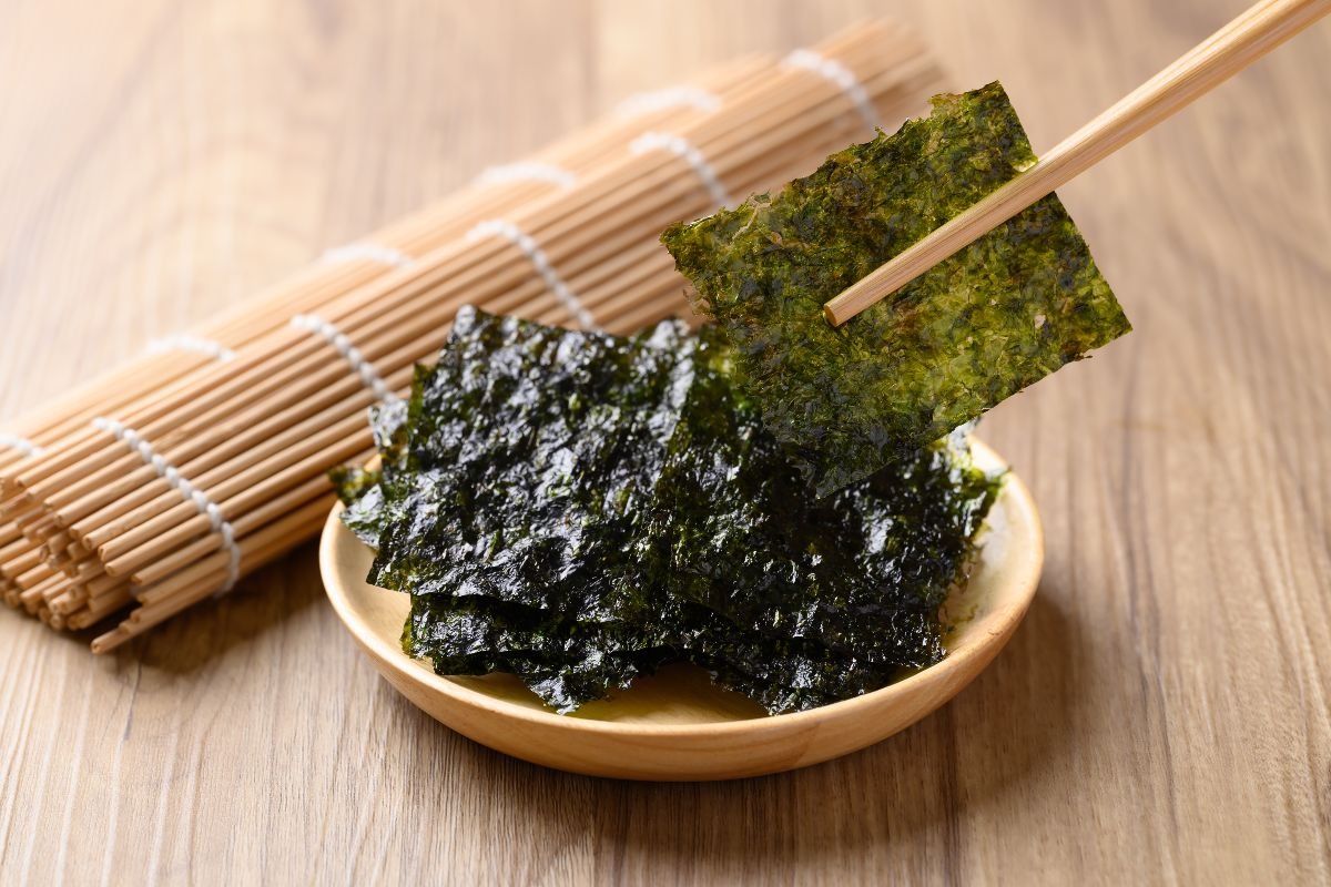 Bacchette che mostrano chips di alga nori posizionate su un piattino