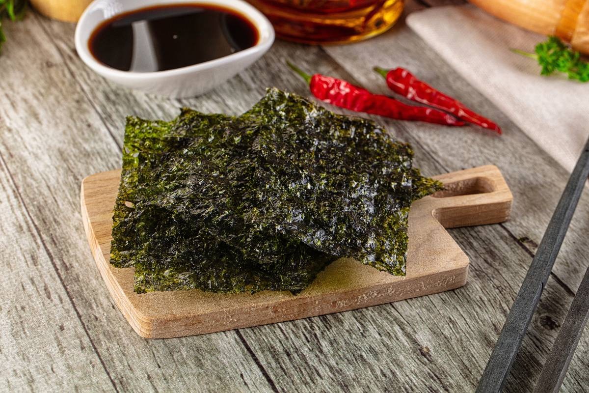 Piccolo tagliere di legno con fogli di alga nori