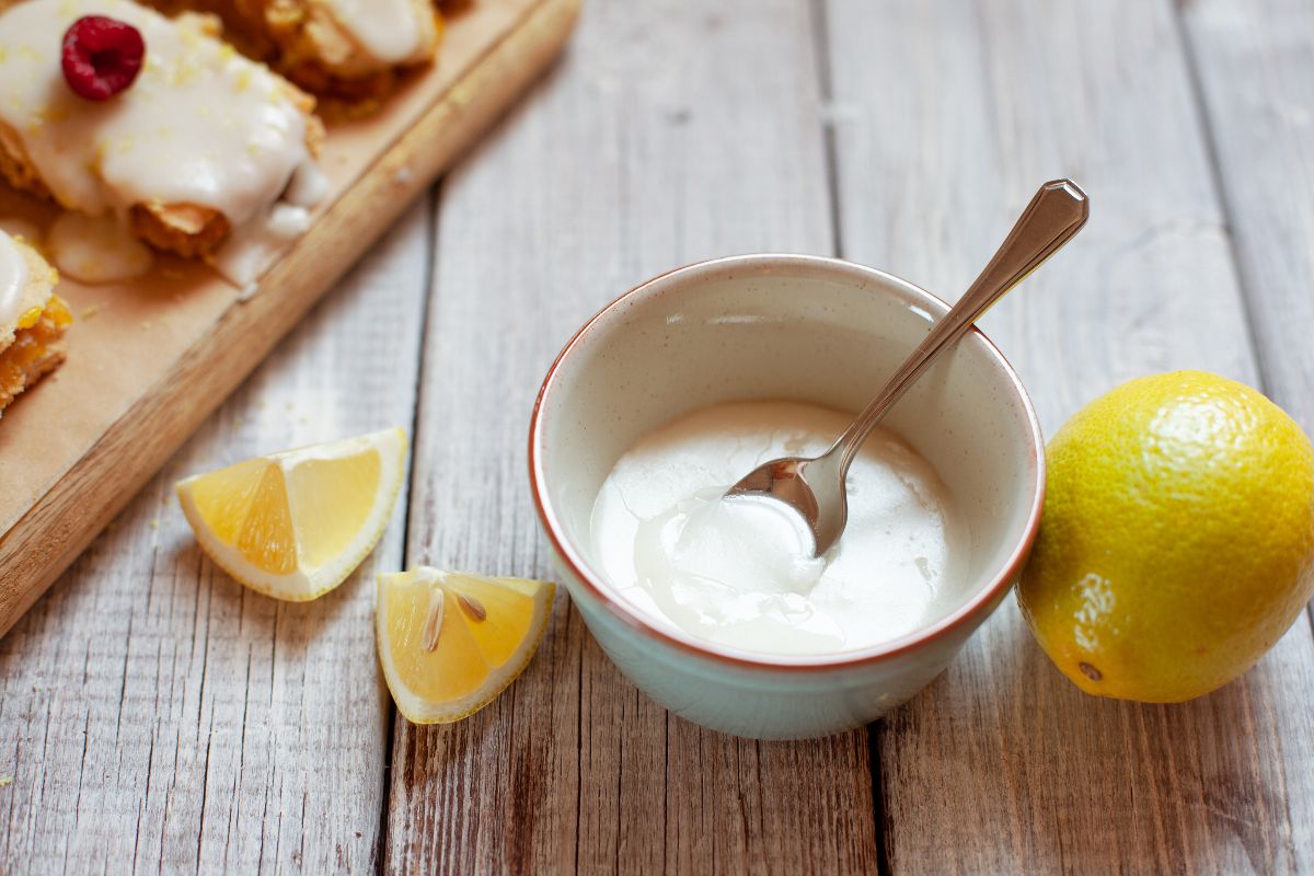 Ciotola di glassa al limone con cucchiaino e vicino limoni
