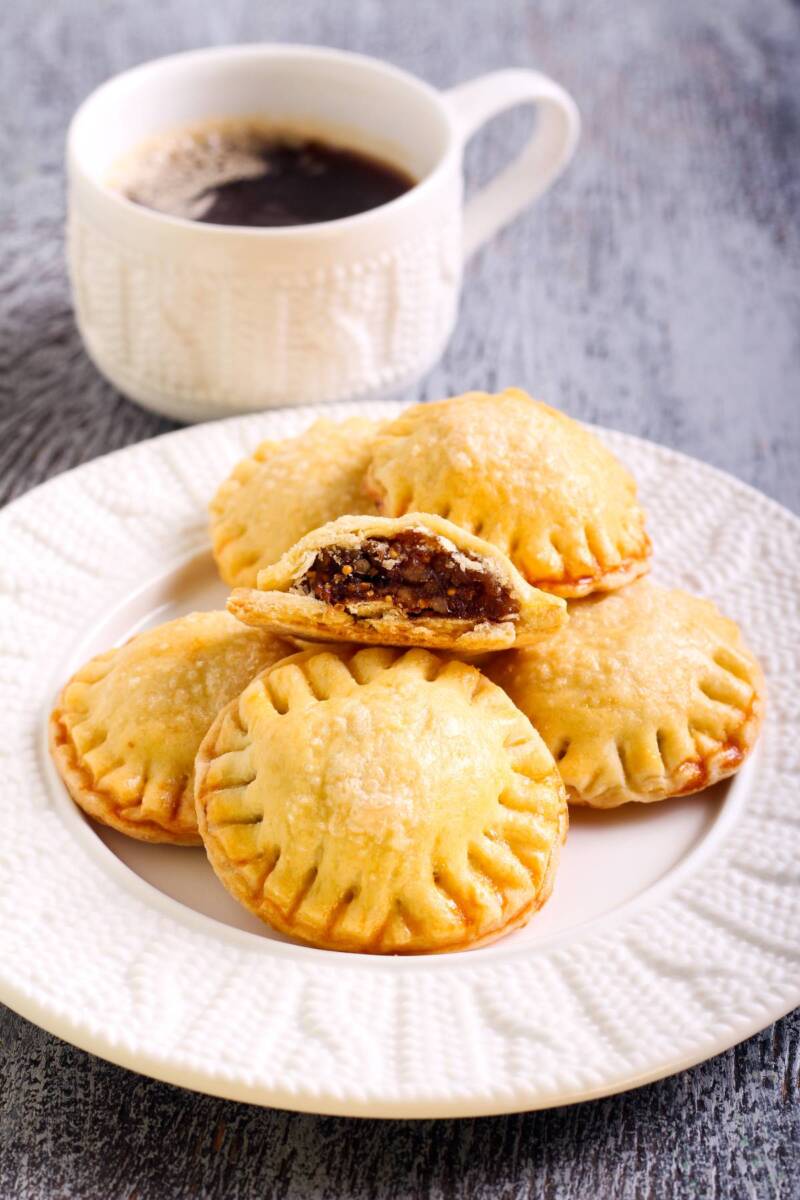 Piattino con dolci di pasta frolla rotondi ripieni vicino a tazzina di caffè