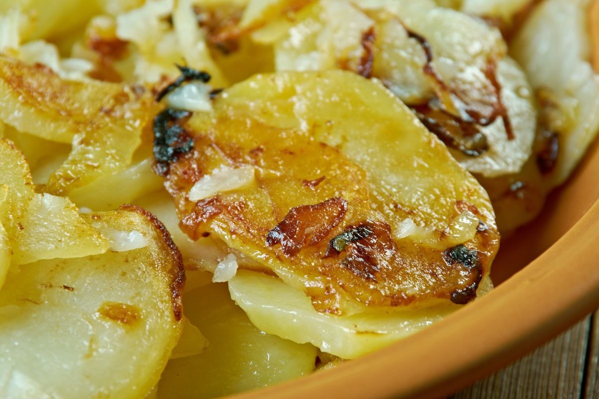 Primo piano patate abbrustolite in padella con cipolle
