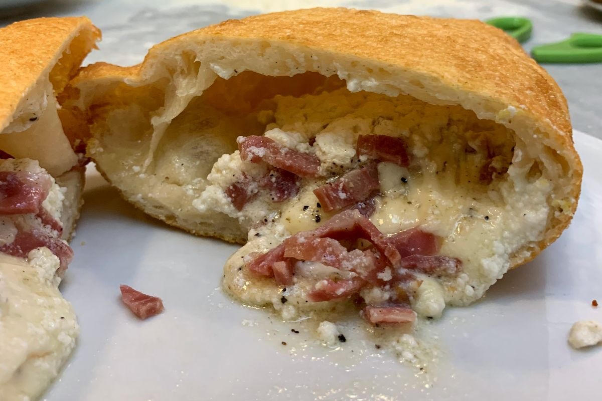 Pizza fritta napoletana tagliata a metà da cui fuoriesce ripieno filante a base di ricotta, provola e salame