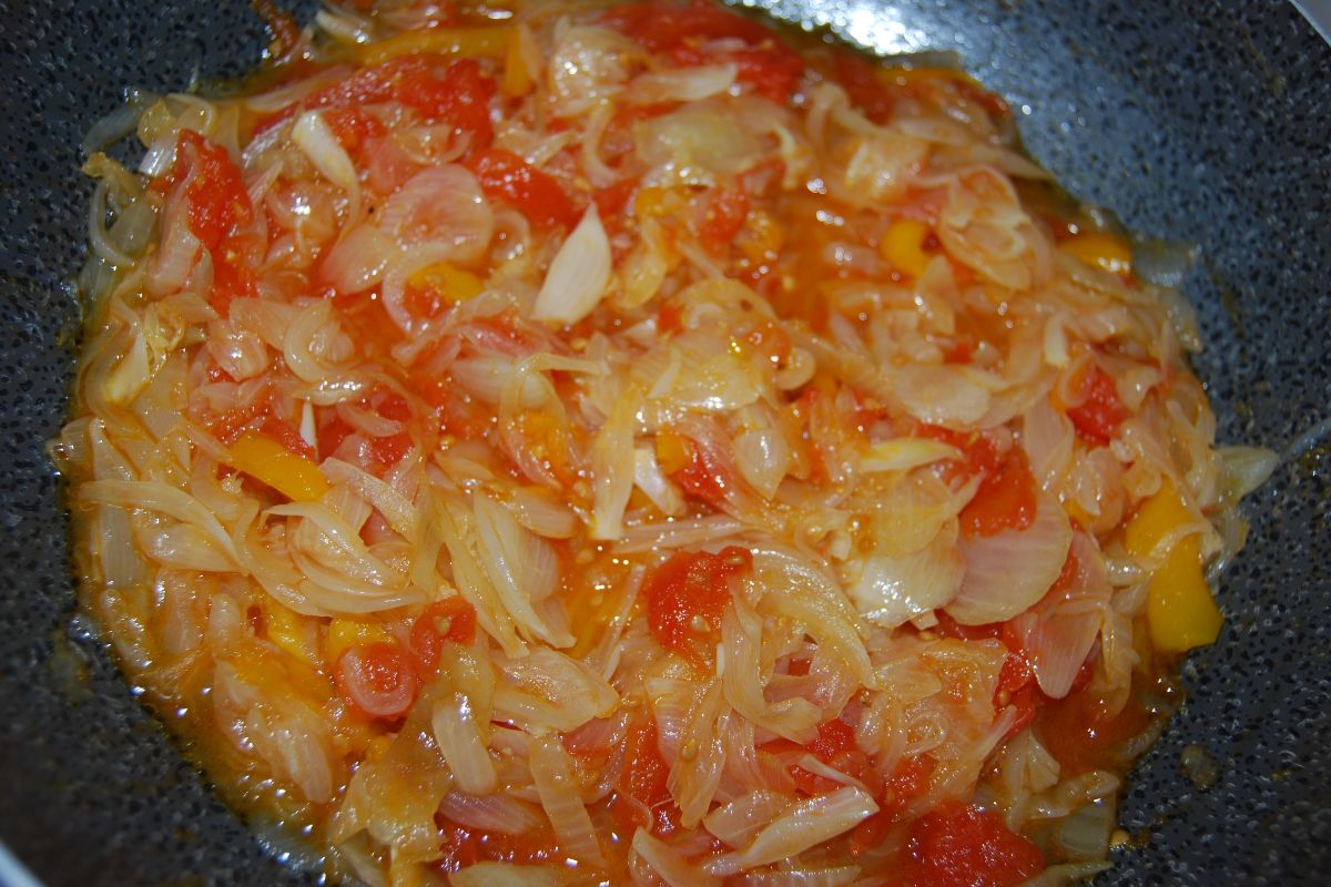 Cipolle bianche e pomodori in cottura in padella