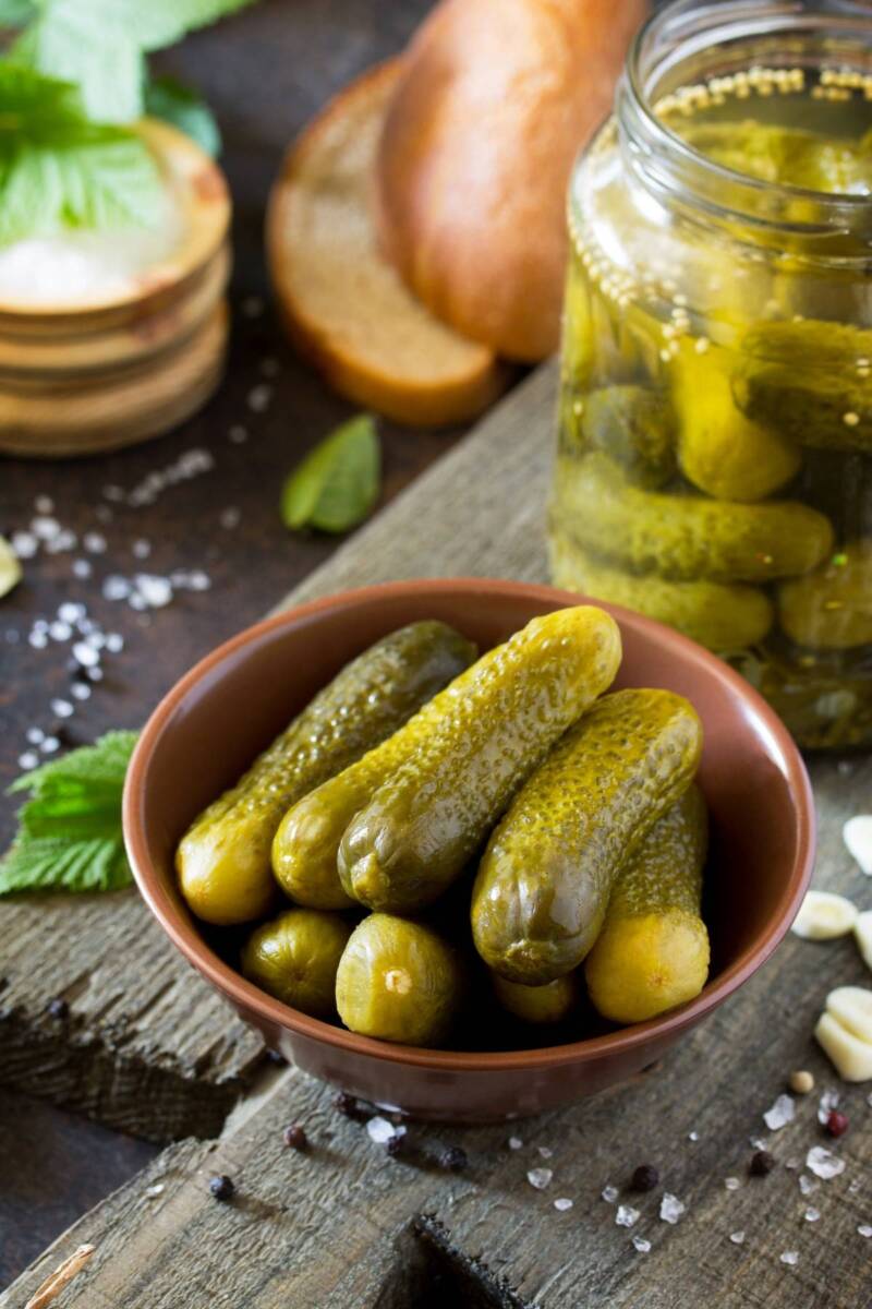 Ciotola con cetriolini sott'aceto presi dal vasetto retrostante