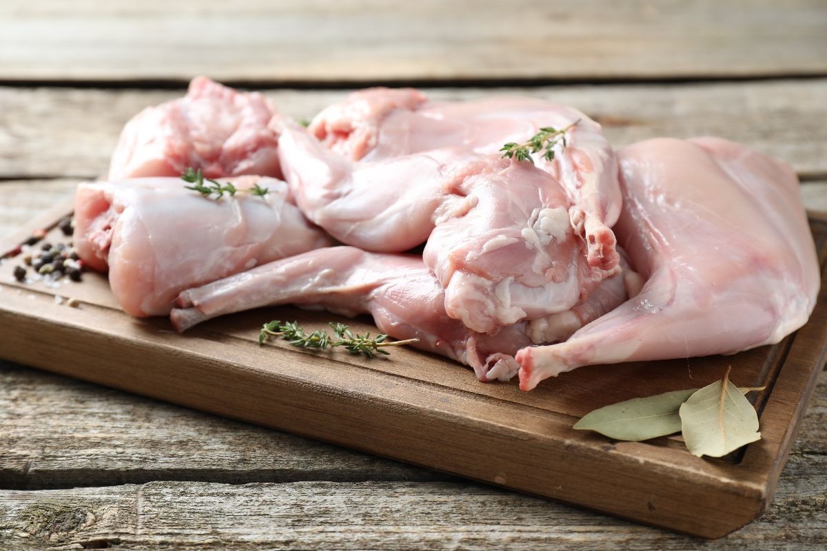 Carne di coniglio a pezzi su tagliere di legno