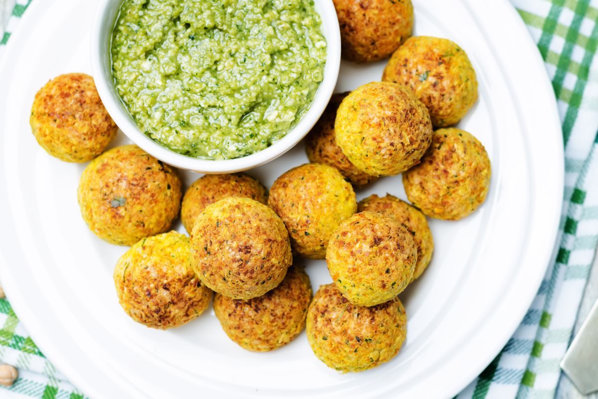Vista dall'alto polpette di farro e verdure su piatto con salsa verde vicino