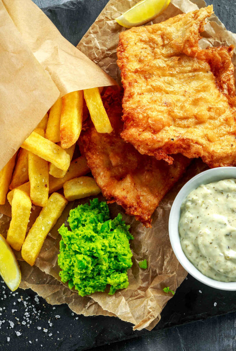 Filetti di pesce fritto serviti con patatine fritte, piselli schiacciati e salsa tartara