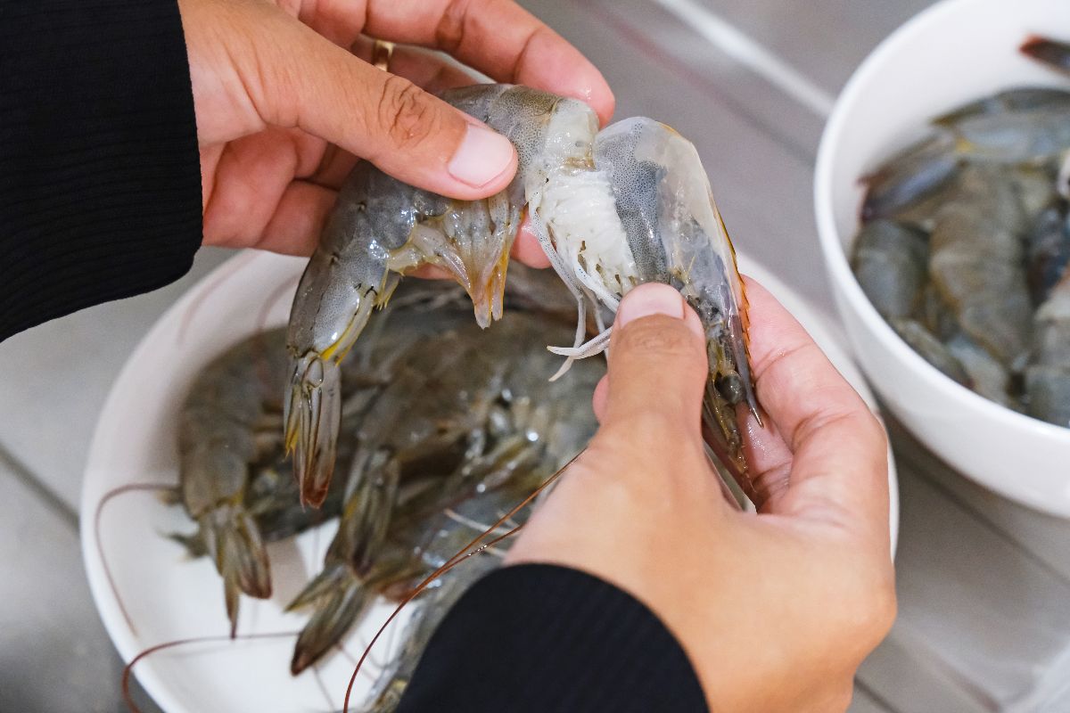 Mani che puliscono i gamberi rimuovendo la testa