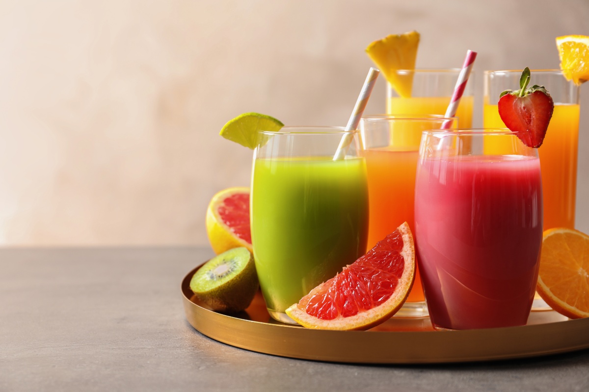 Bicchieri con succhi di frutta diversi (kiwi, ananas, fragola, arancia) su vassoio