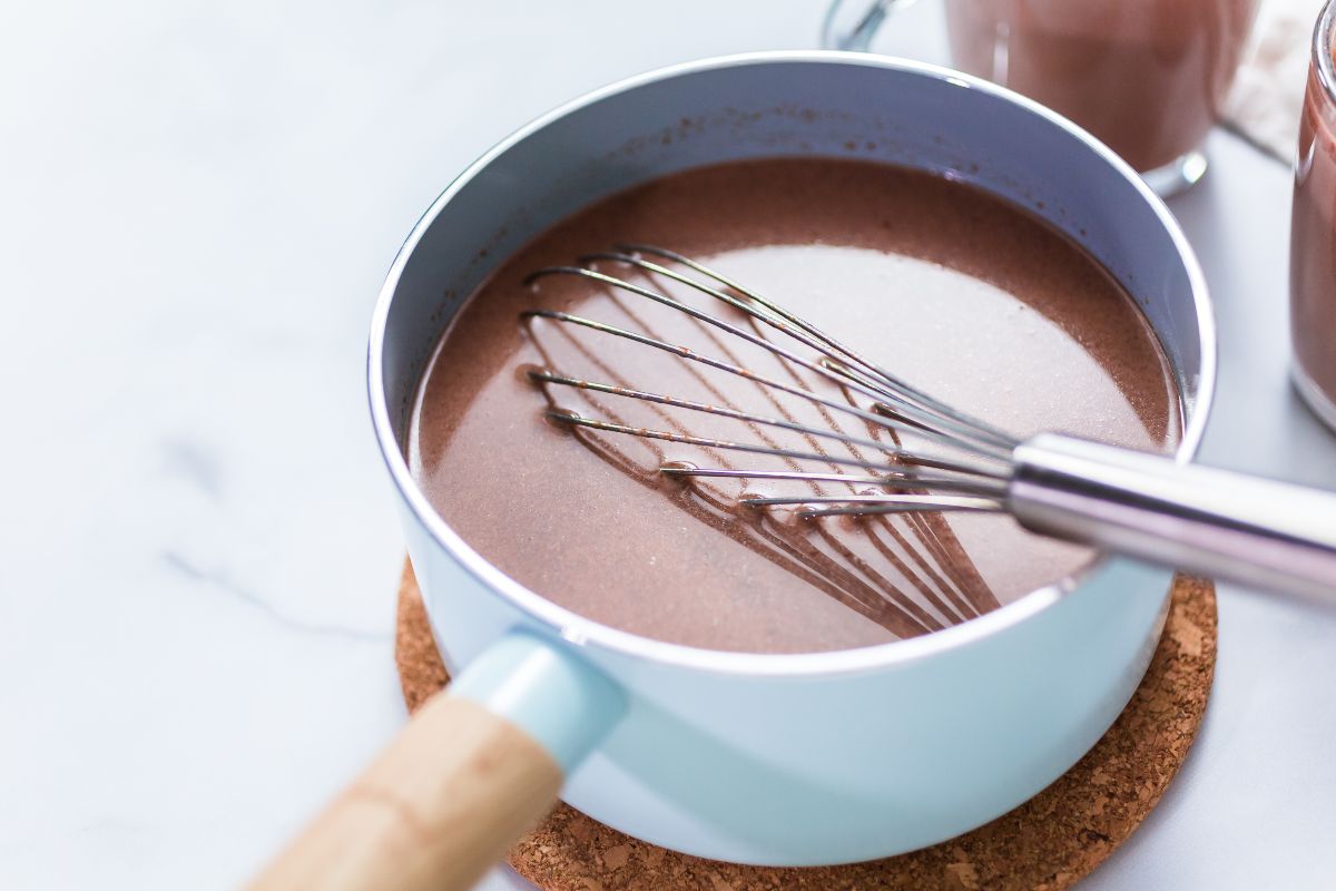 Pentolino con cioccolata calda e frusta da cucina