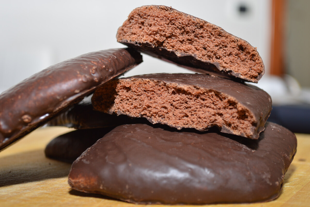 Biscotti mostaccioli coperti di cioccolato con un biscotto spezzato a metà in primo piano