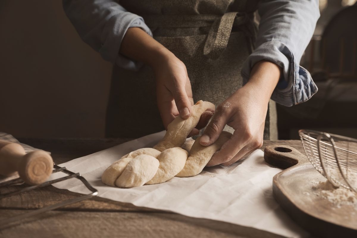 Mani di donna che intrecciano impasto pane lievitato