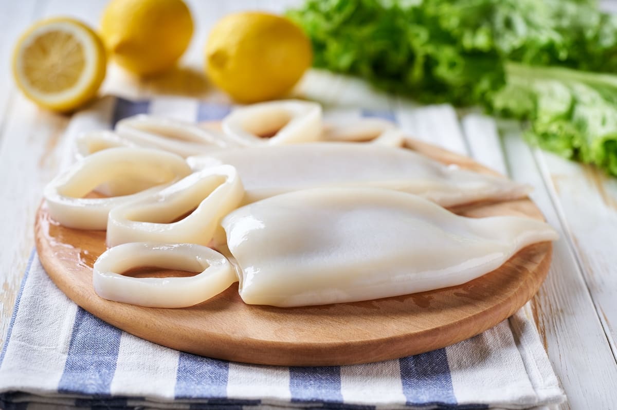 Tagliere di legno con calamari puliti interi e tagliati ad anelli