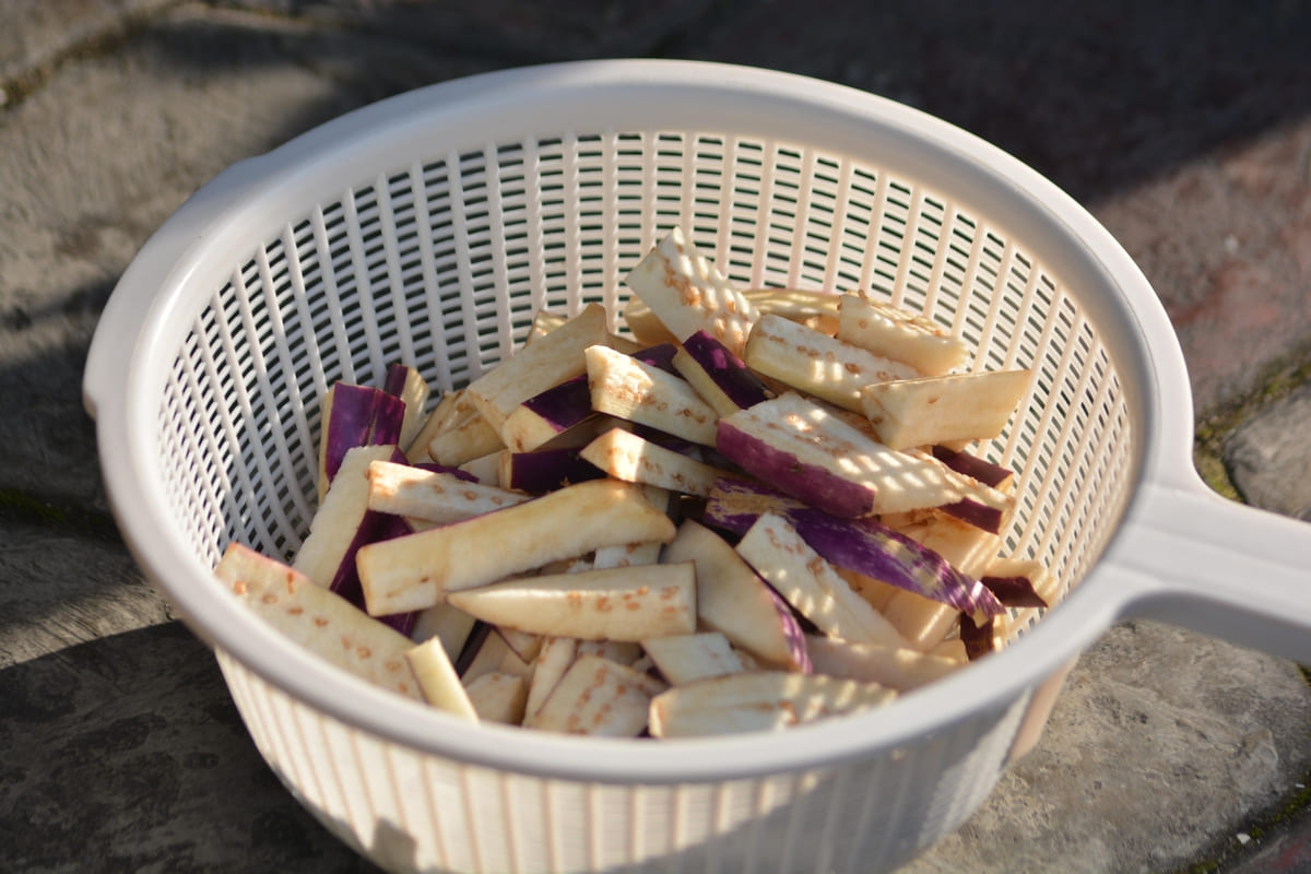 Scolapasta di plastica con melanzane tagliate a bastoncini