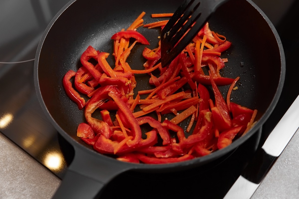 Peperoni tagliati a strisce che cuociono in padella