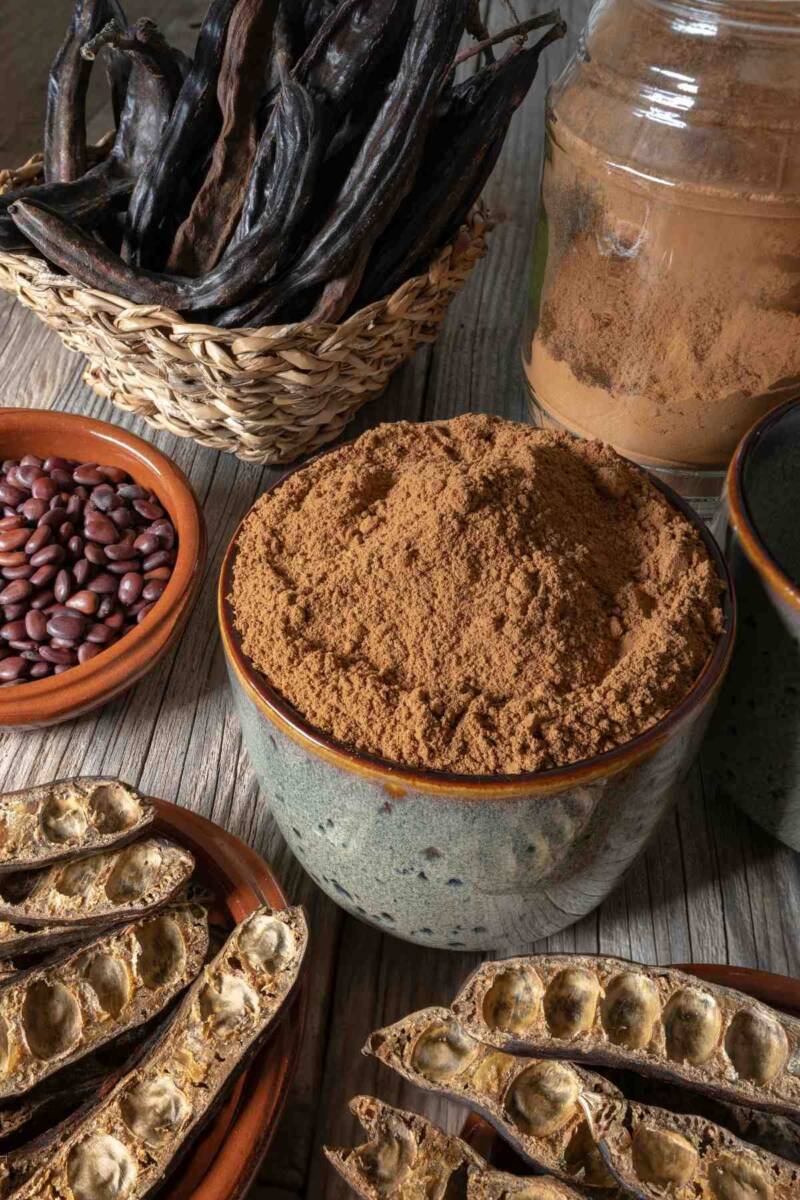 Carrube aperte e chiuse con ciotola con farina di carrube