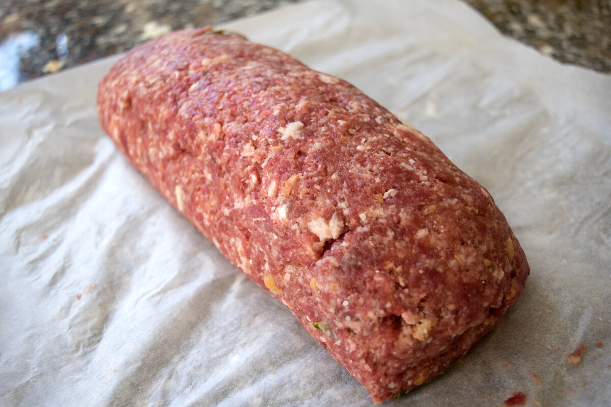 Polpettone di carne macinata ancora da cuocere su foglio di carta forno