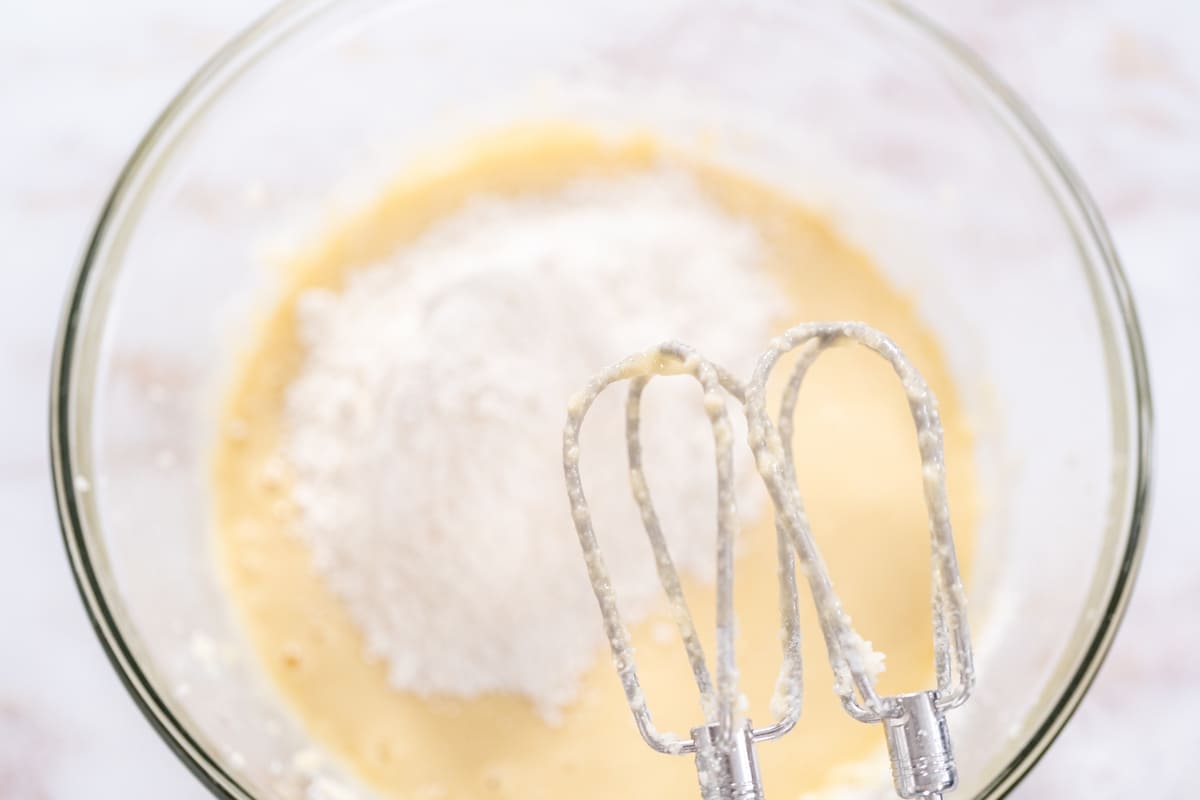 Vista dell'alto ciotola con fruste elettriche e impasto torta