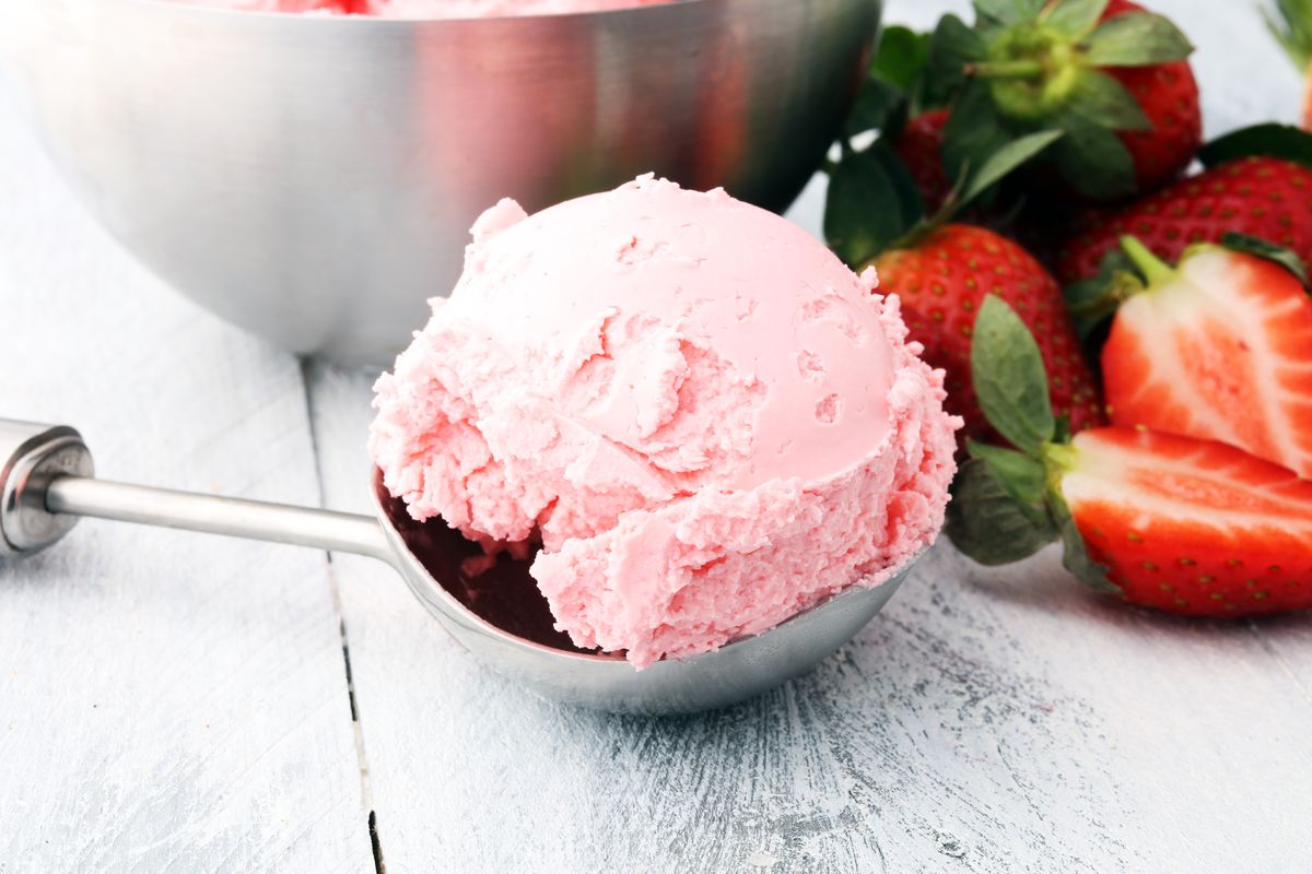 Pallina di gelato in spallinatore con fragole fresche