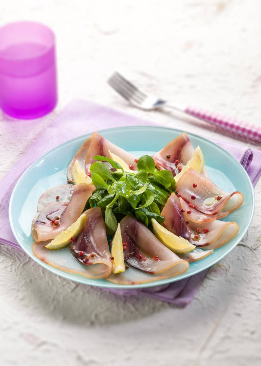 Piatto con carpaccio di pesce spada, rucola e limone a fette