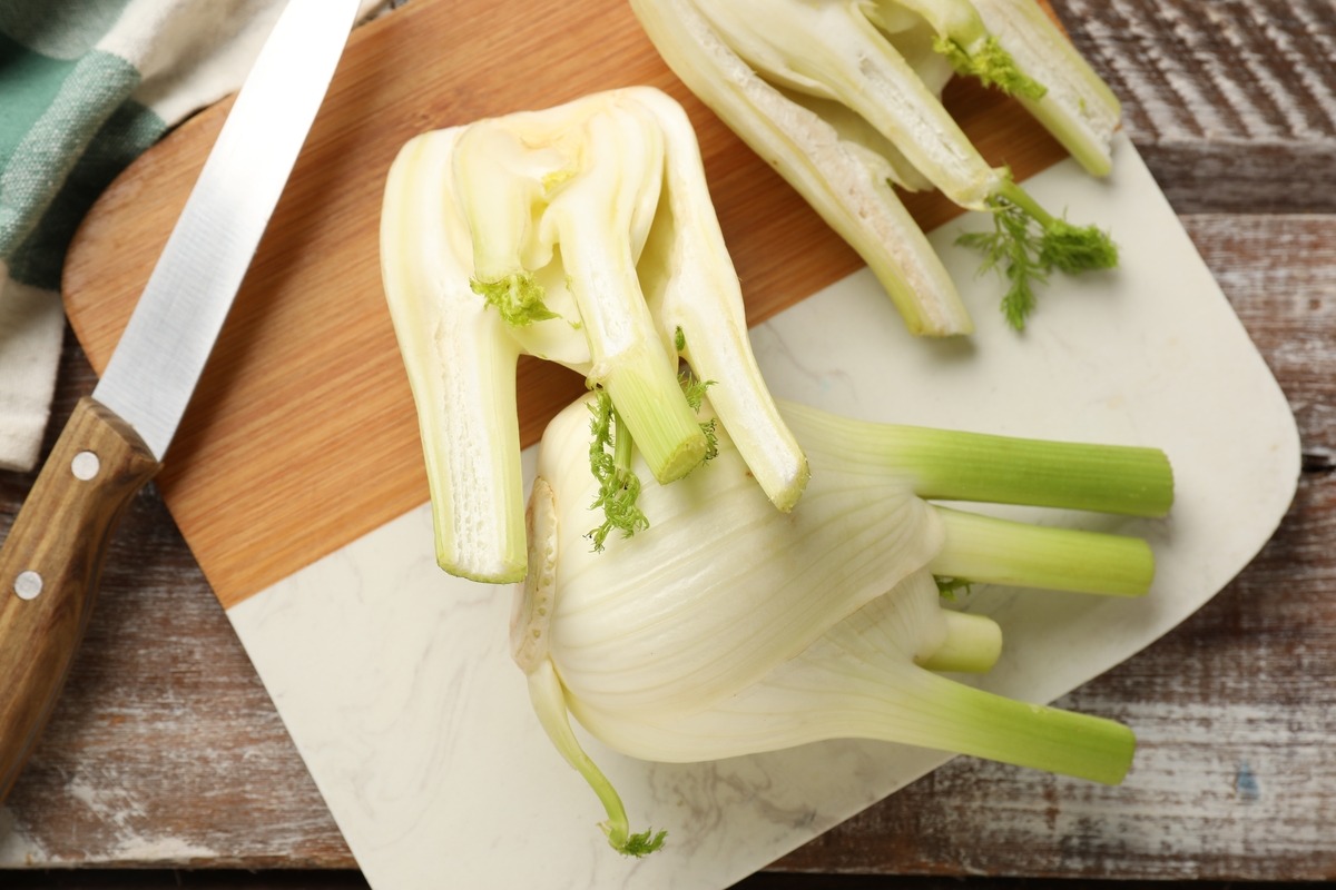 Vista dall'alto finocchi tagliati a metà con coltello su tagliere