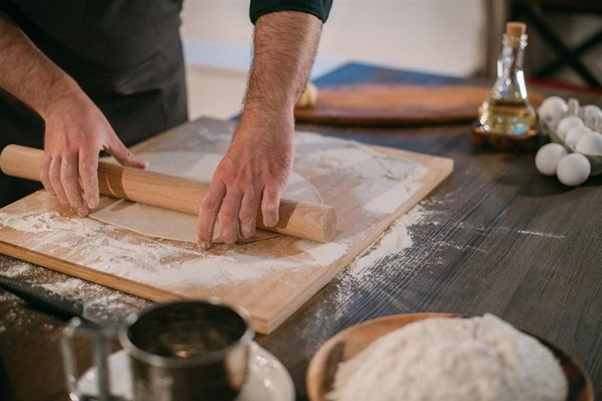 Mani che stendono con il mattarello la pasta fresca