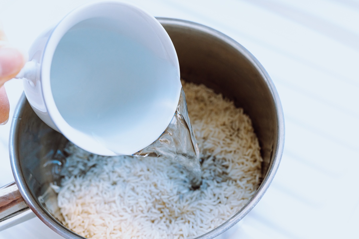 Versare acqua in pentola con riso per cottura pilaf