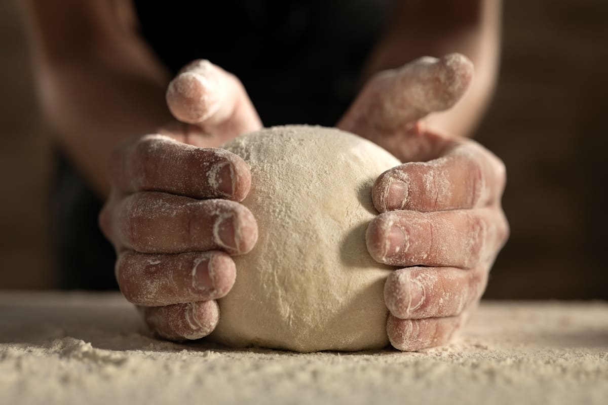 Mani che lavorano impasto a base di farina e acqua