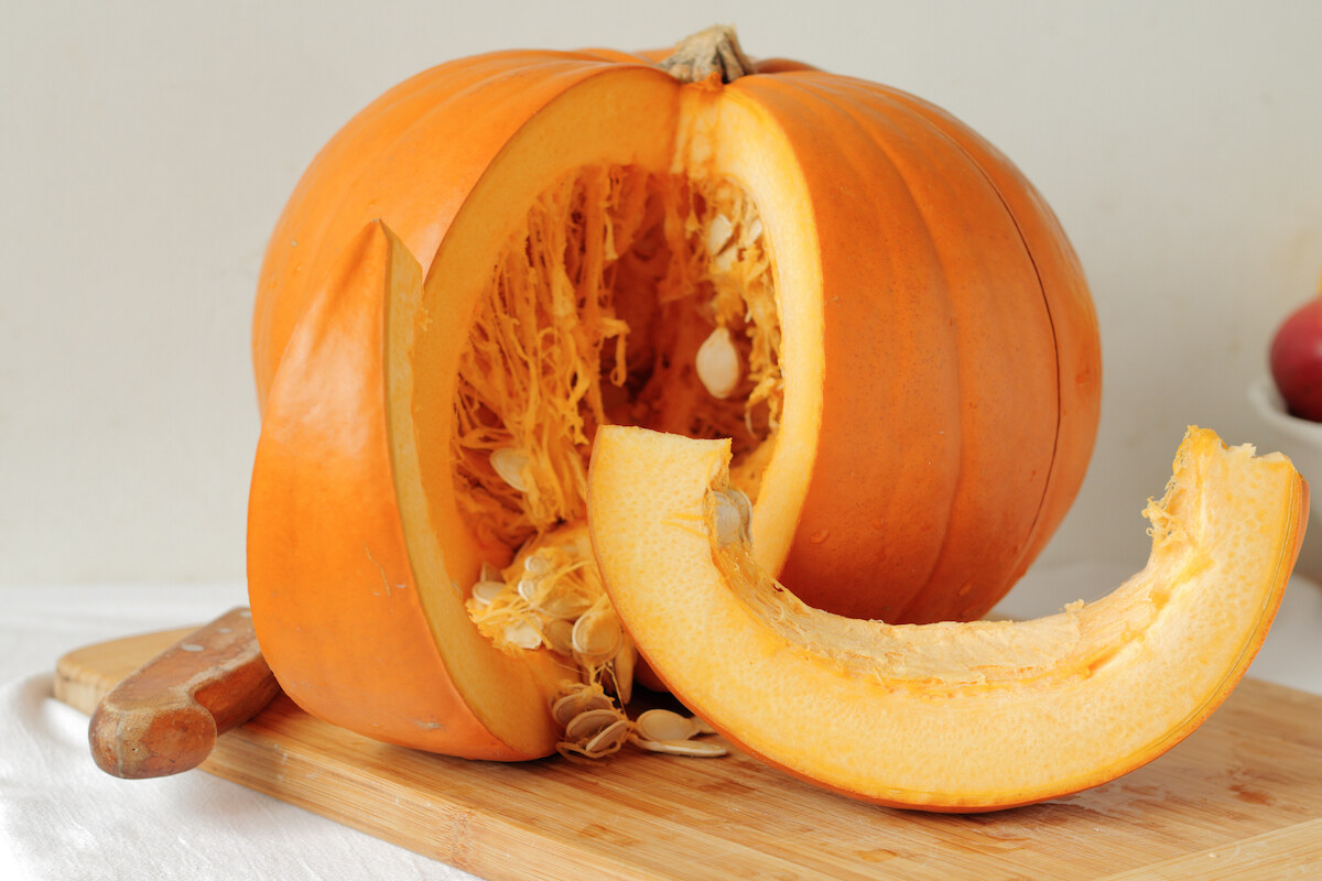 Zucca arancione tagliata a fette su tagliere di legno