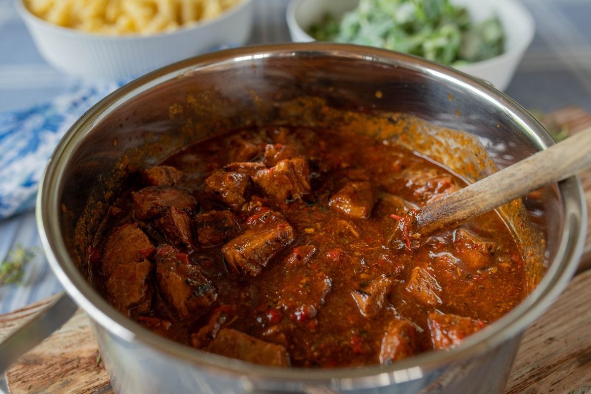 Pentola con carne in cottura con sugo di pomodoro