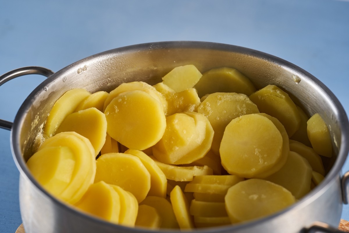 Pentola con patate bollite e tagliate a fette