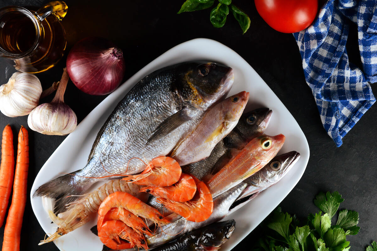 Pesce fresco e gamberi su piatto con ingredienti per brodetto alla vastese