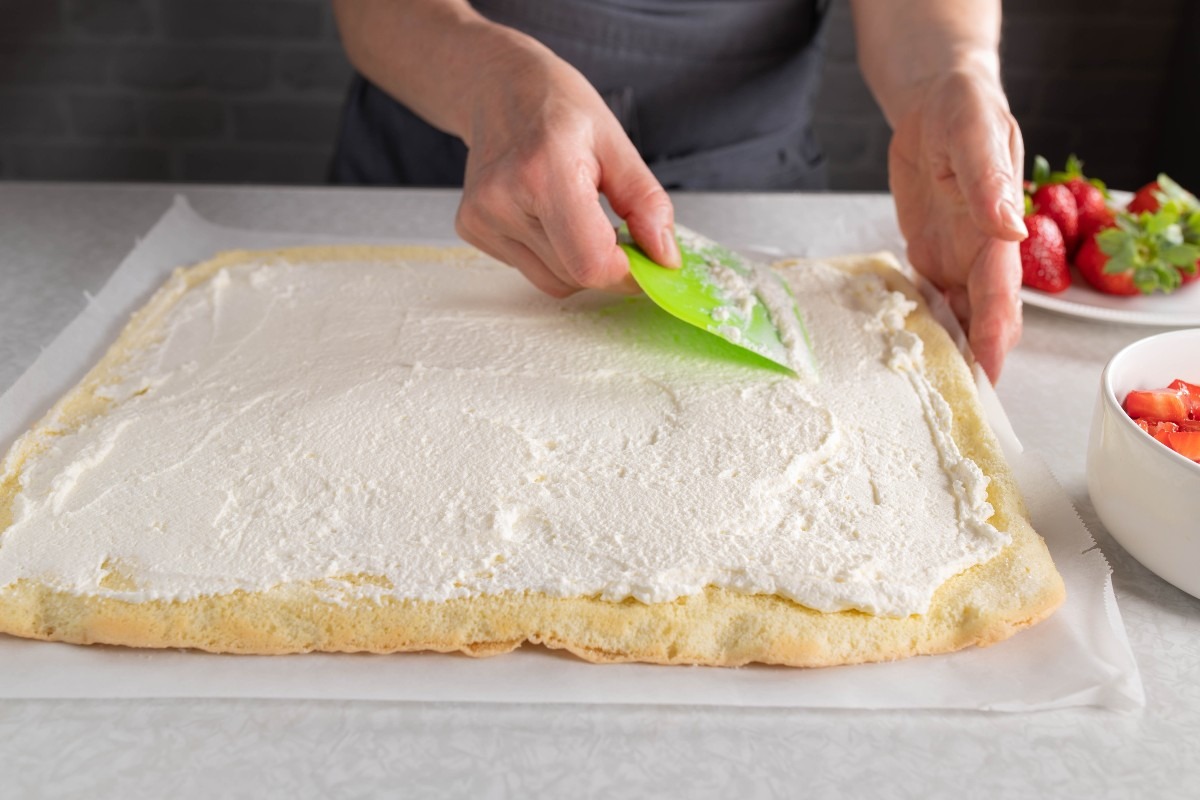 Panna montata allargata su pasta biscotto con l'aiuto di una spatola