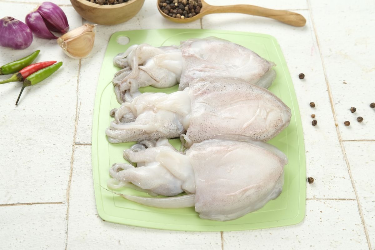 Seppie fresche su tagliere da cucina con vicino aglio e peperoncino