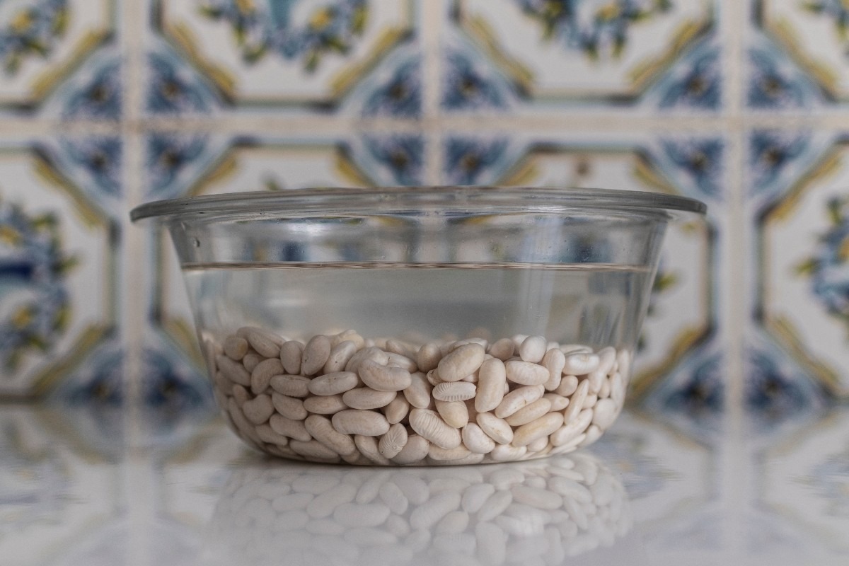 Ciotola di vetro con fagioli cannellini in ammollo in acqua